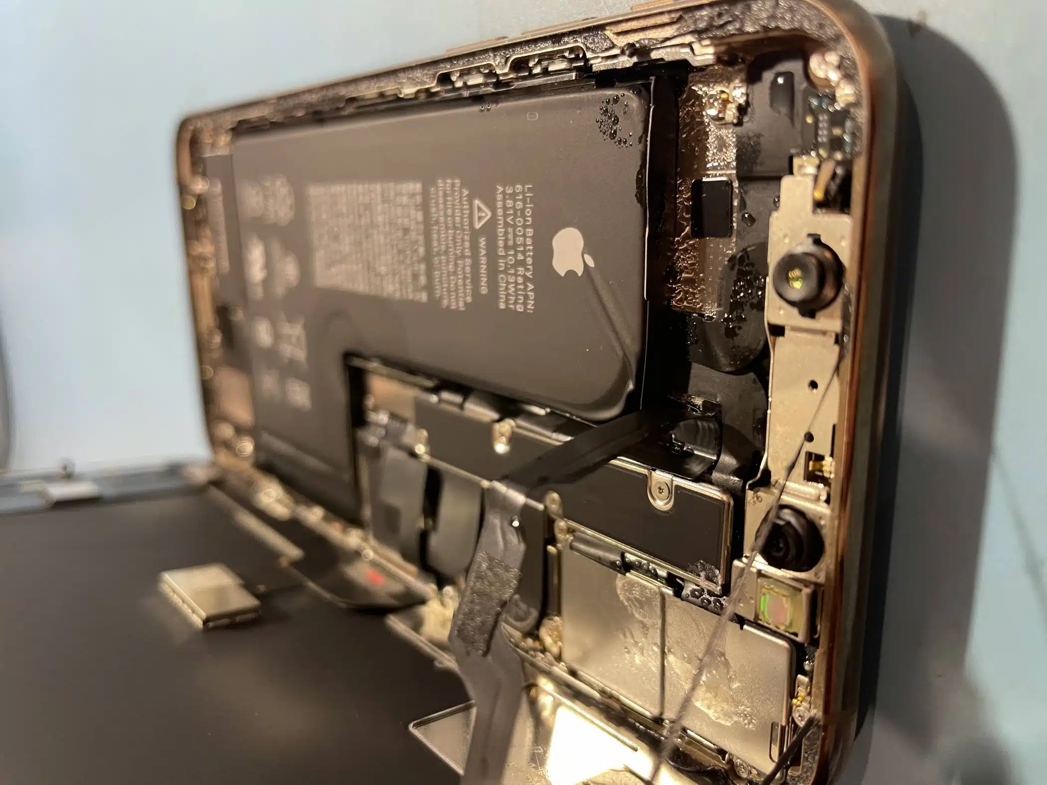 An iPhone that has been opened to show severe liquid damage on the inside of the device