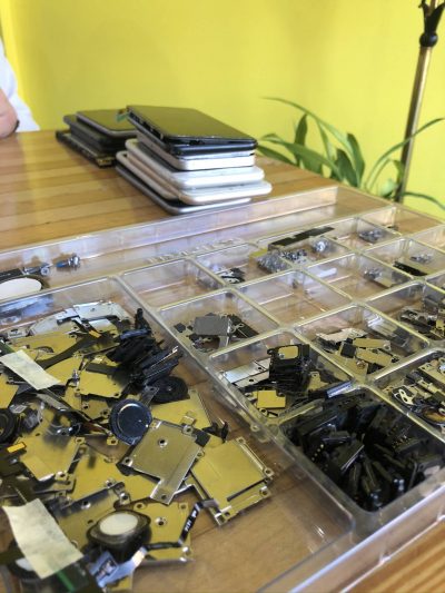 Pieces of electronic devices sorted into pieces on a tabletop ready for electronic recycling at The Lab