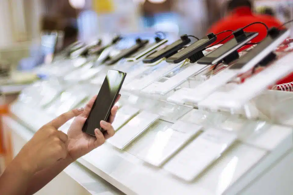 Hands holding a refurbished smartphone at a display in a store