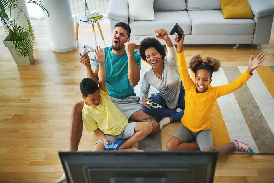 Black family sitting on a rug playing video games as a family
