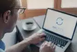 Man typing on a laptop computer while wearing glasses.