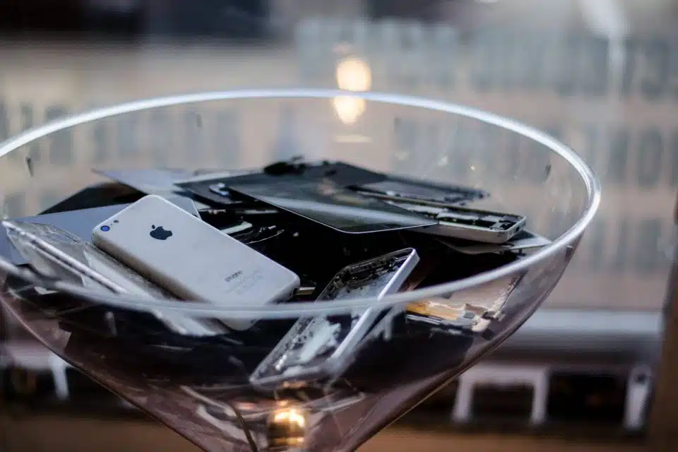 Damaged cell phones piled in a clear glass bowl