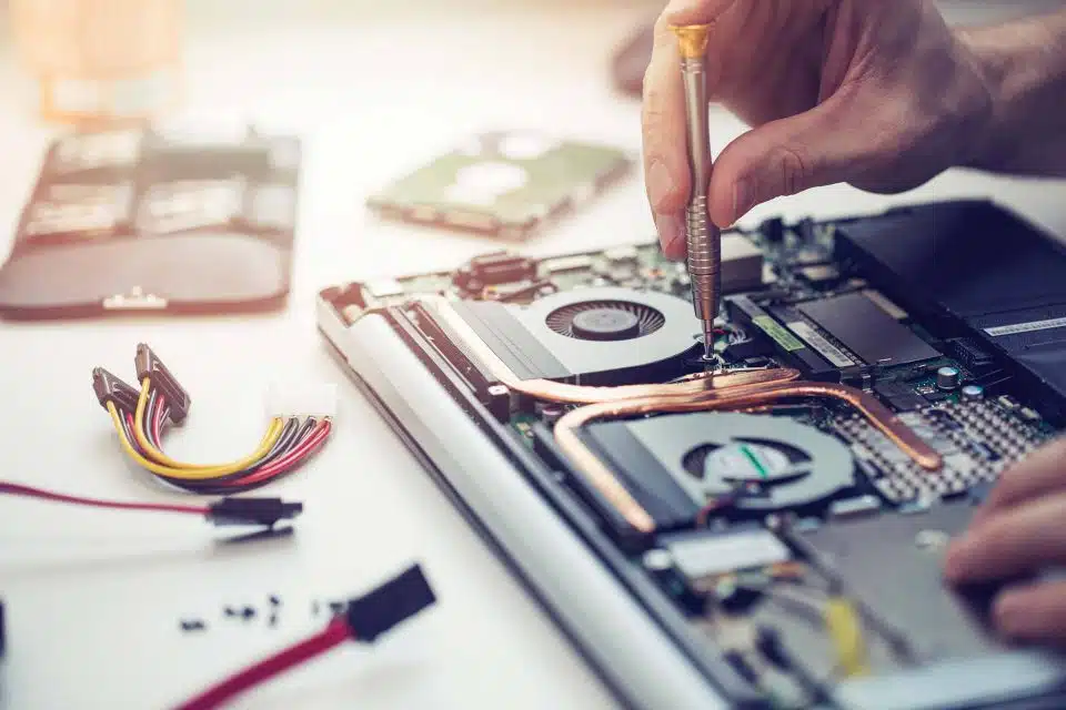 Hands using a small screwdriver to repair the inside of a computer laptop